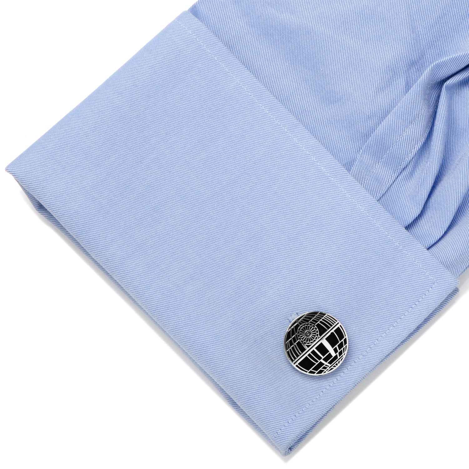 Cufflink on a light blue shirt with a white background