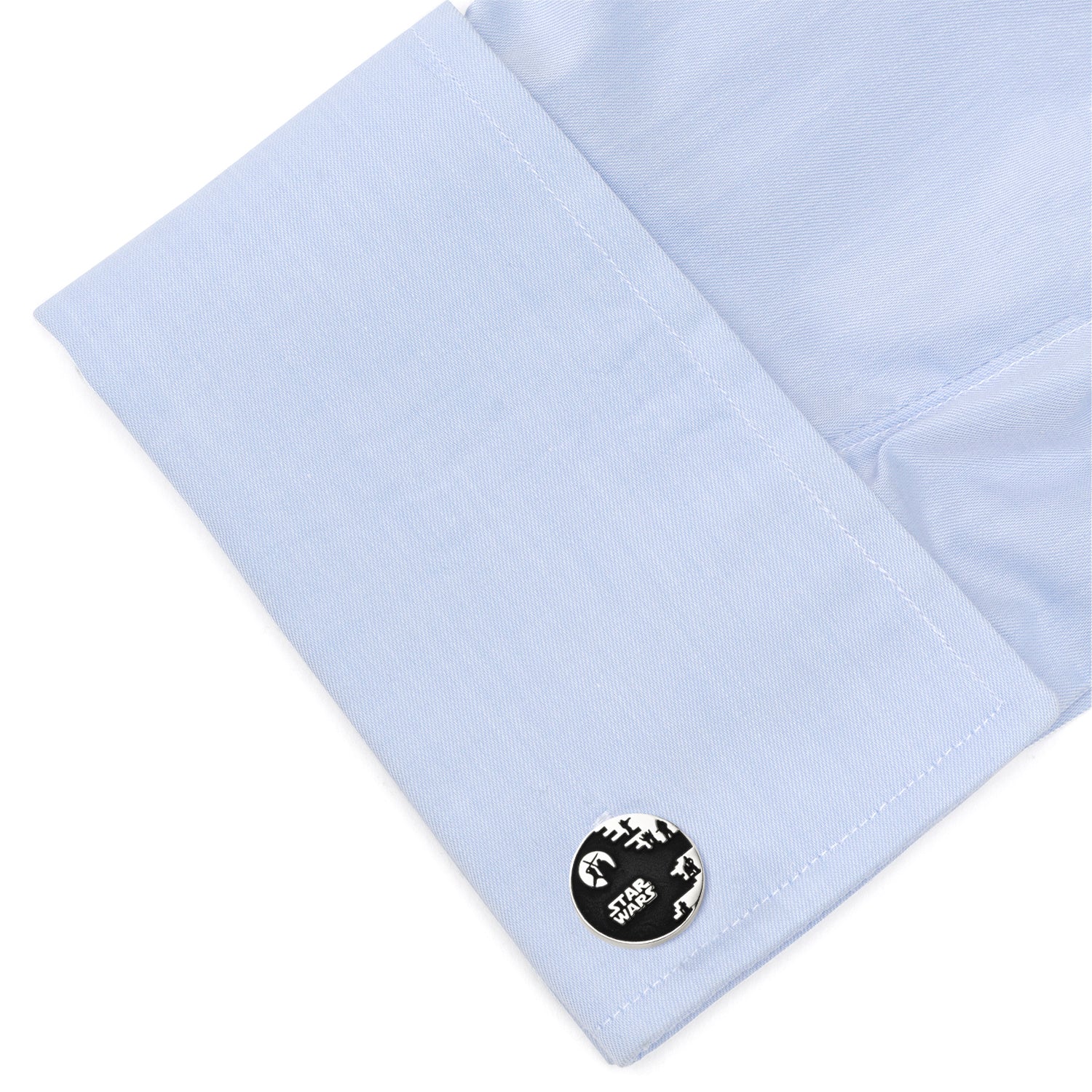 Close-up of light blue shirt cuff with a round black and white emblem.