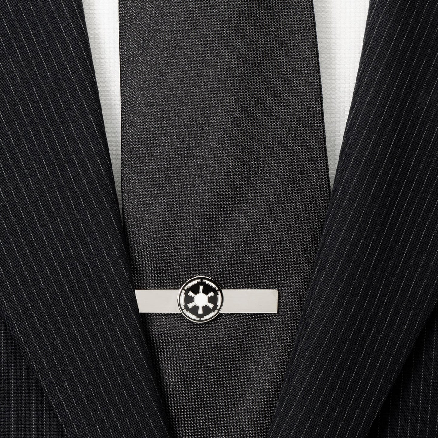 Black tie with a silver tie clip on a black pinstripe suit jacket.