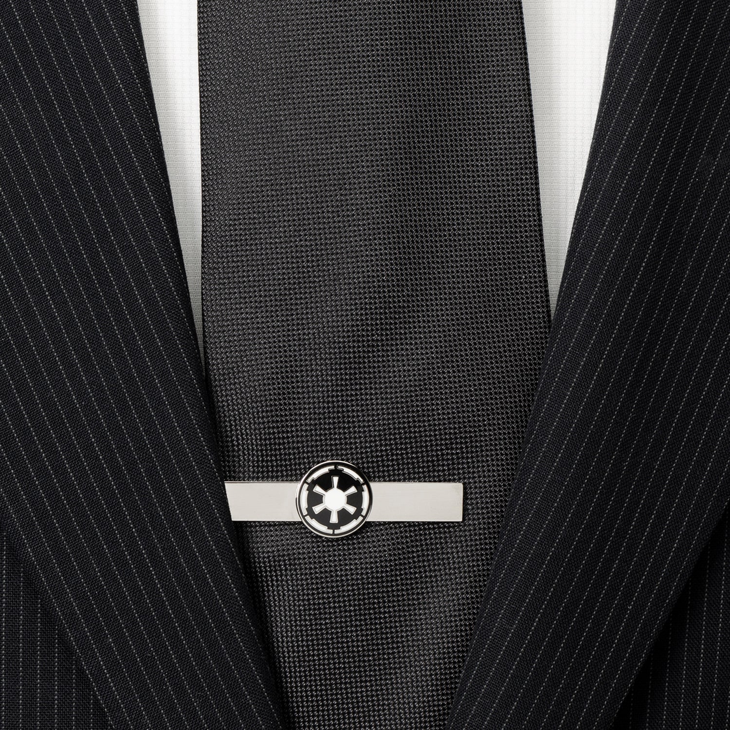 Black tie with a silver tie clip on a black pinstripe suit jacket.