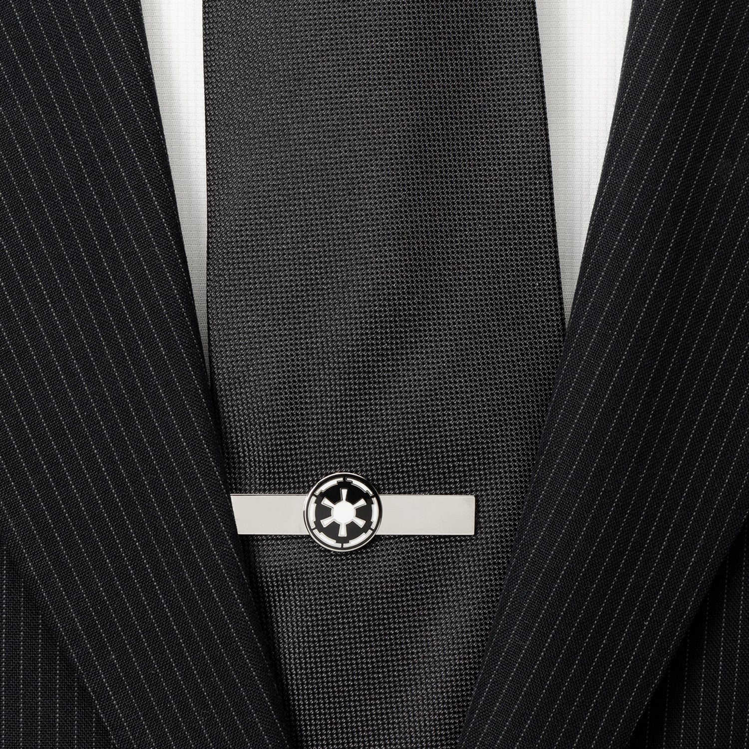 Black tie with a silver tie clip on a black pinstripe suit jacket.
