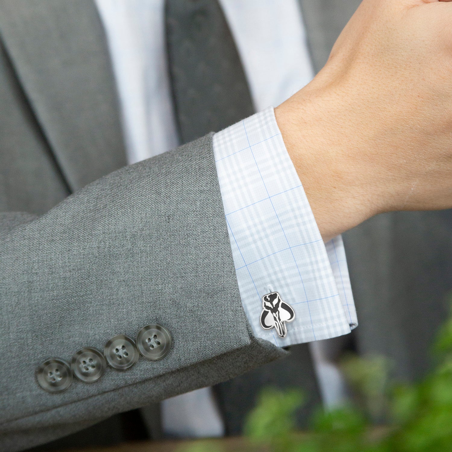 Gray suit jacket with white shirt cuff and clover cufflink, blurred background