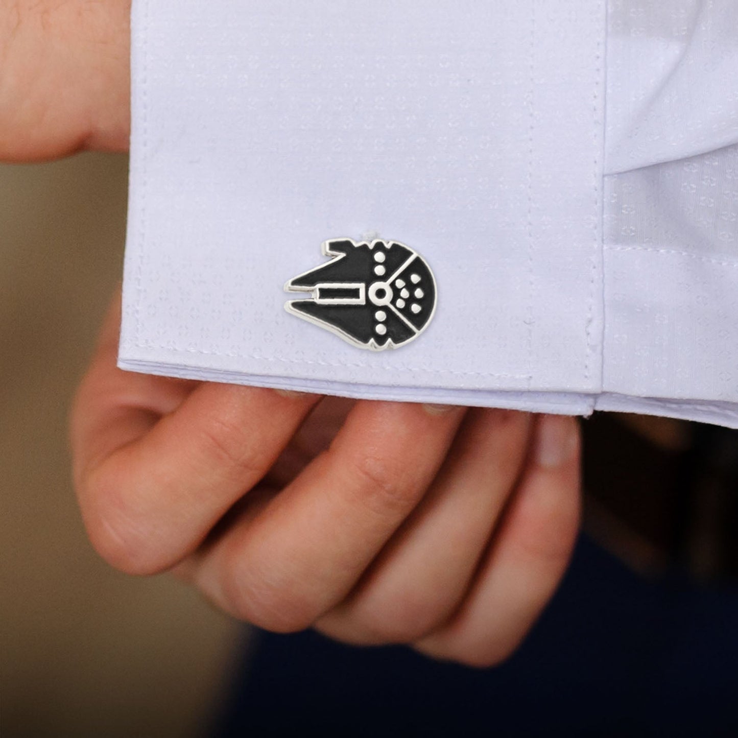 Cufflink shaped like a spaceship on a white shirt sleeve