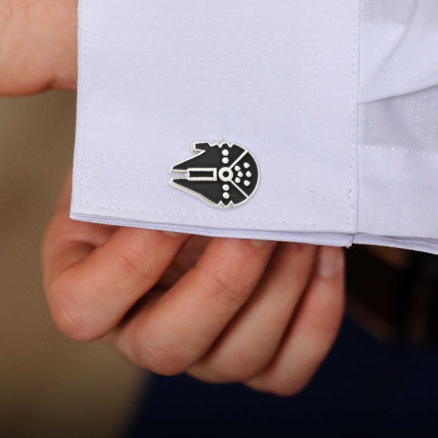 Cufflink shaped like a spaceship on a white shirt sleeve