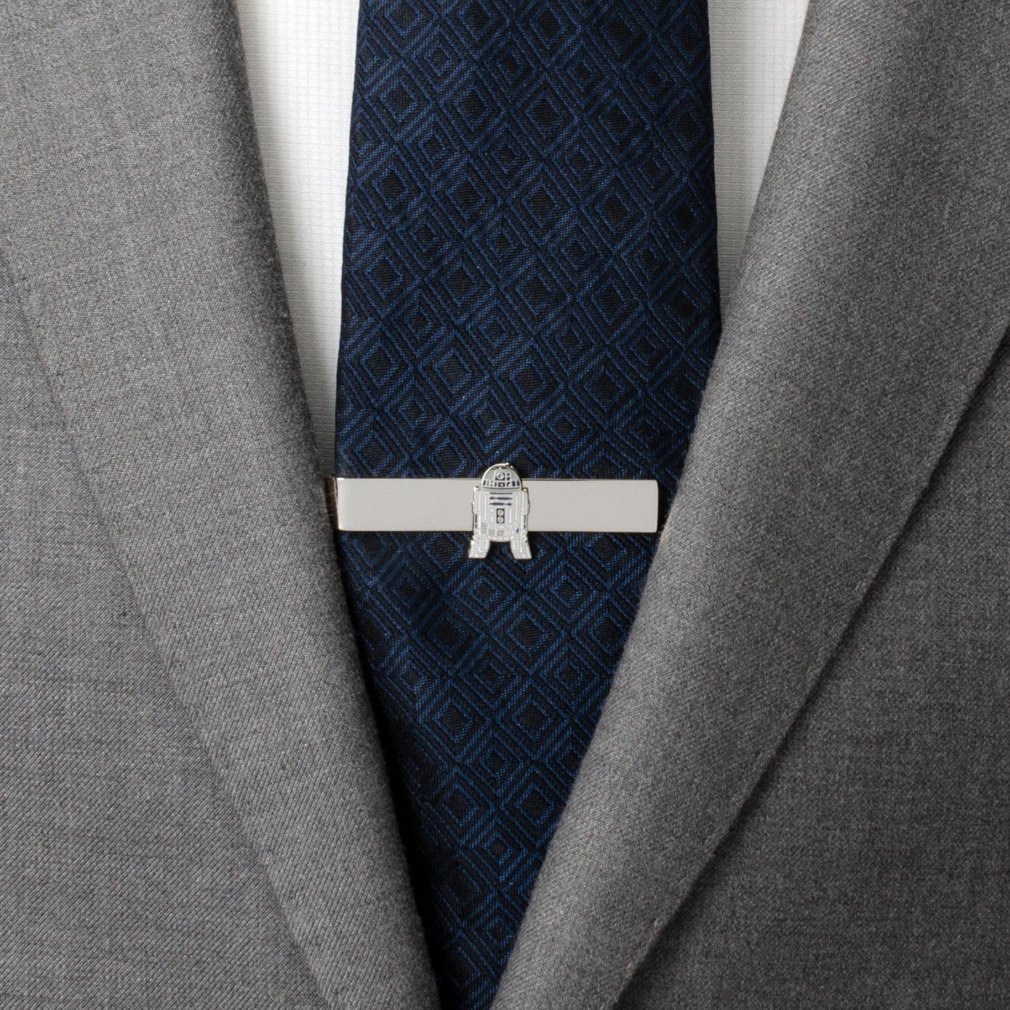 Gray suit jacket with a blue patterned tie and a silver tie clip on a white background