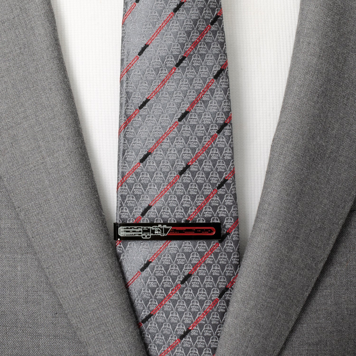 Gray tie with red and black patterns worn with a gray suit jacket.