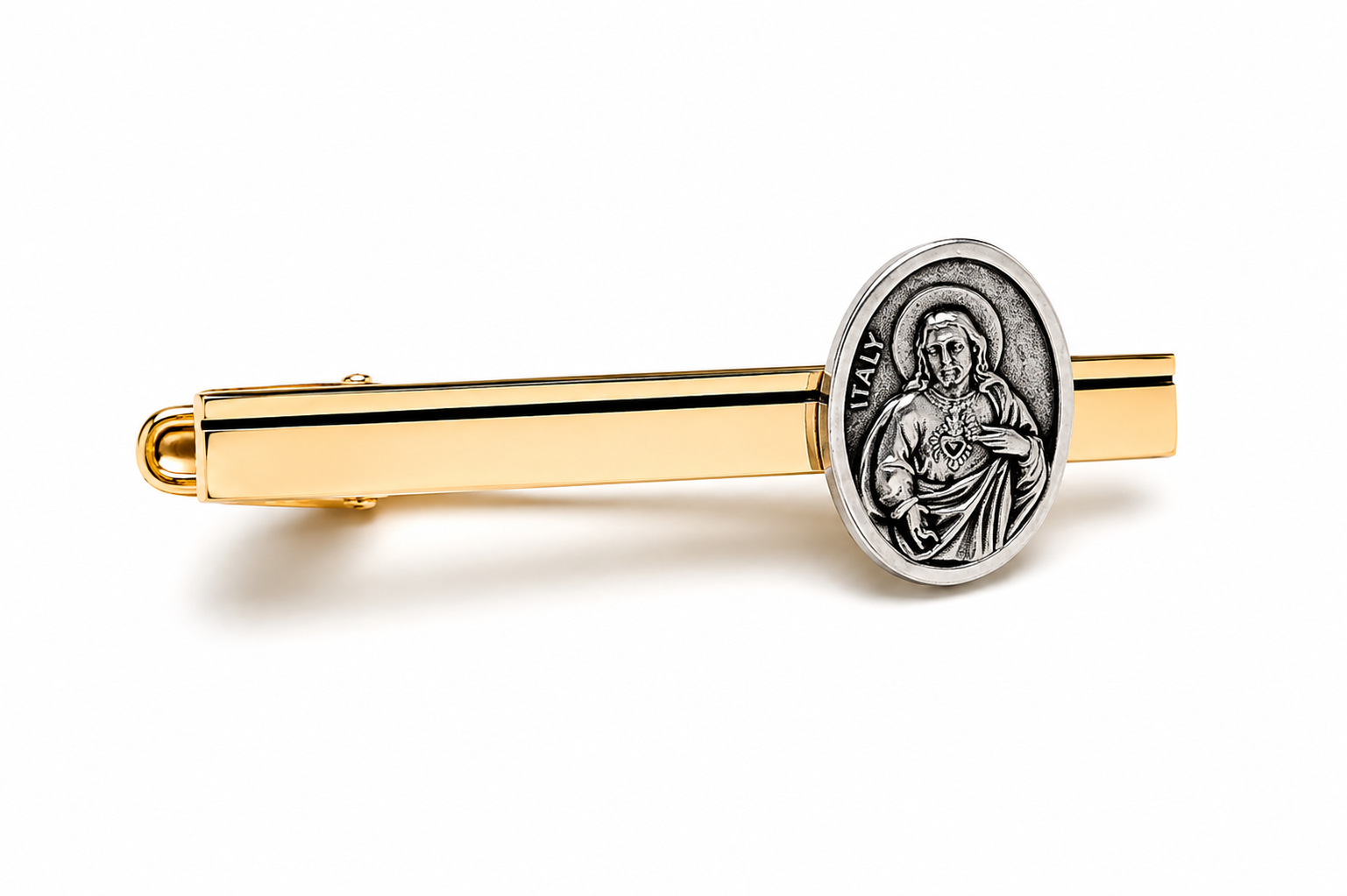A gold and silver tie clip featuring a circular silver Jesus medal on a polished gold bar, set against a clean white background.