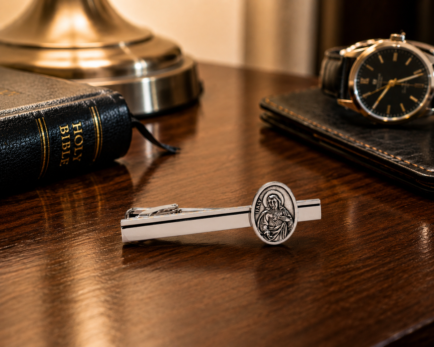Sacred Heart of Jesus tie clip displayed beside formal accessories and Bible