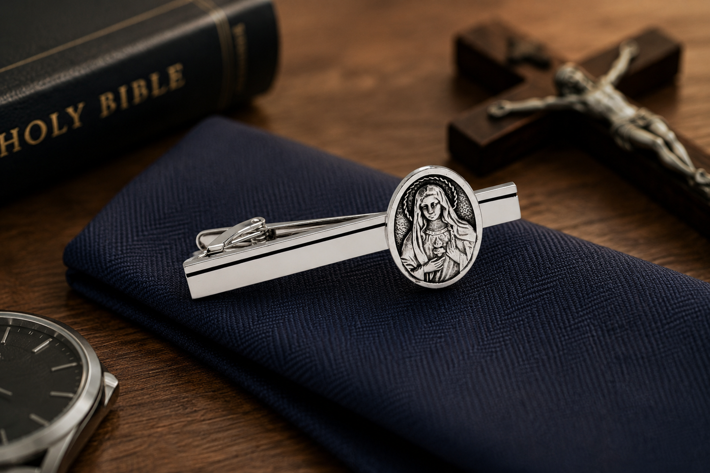 Silver tie clip with religious design on a blue pocket square, with a Bible and cross in the background. Mother Mary