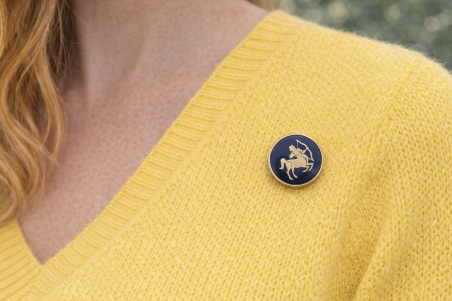 Person wearing a yellow sweater with a blue Sagittarius Zodiac Archer Lapel Pin  featuring a zodiac sign.
