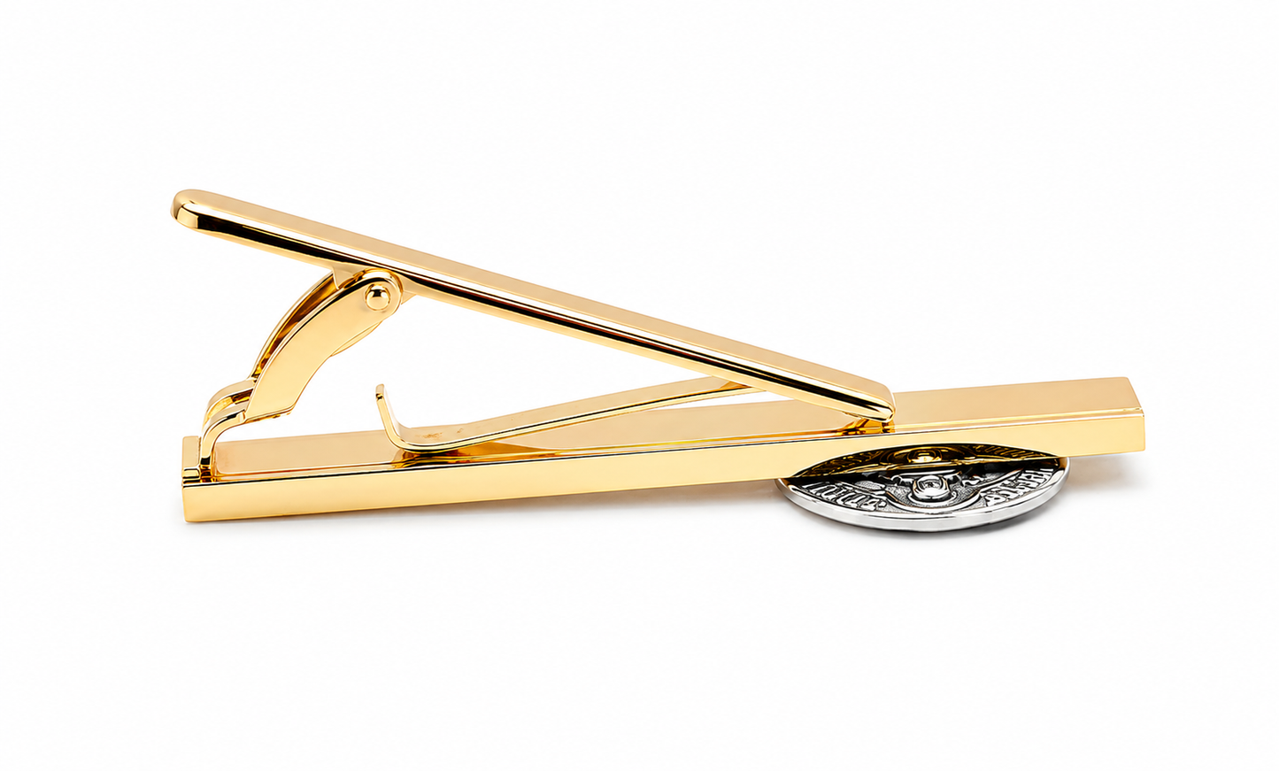 A gold-plated tie clip with a polished rectangular bar, spring-loaded hanger, and a round silver-toned decorative emblem on a clean white background.