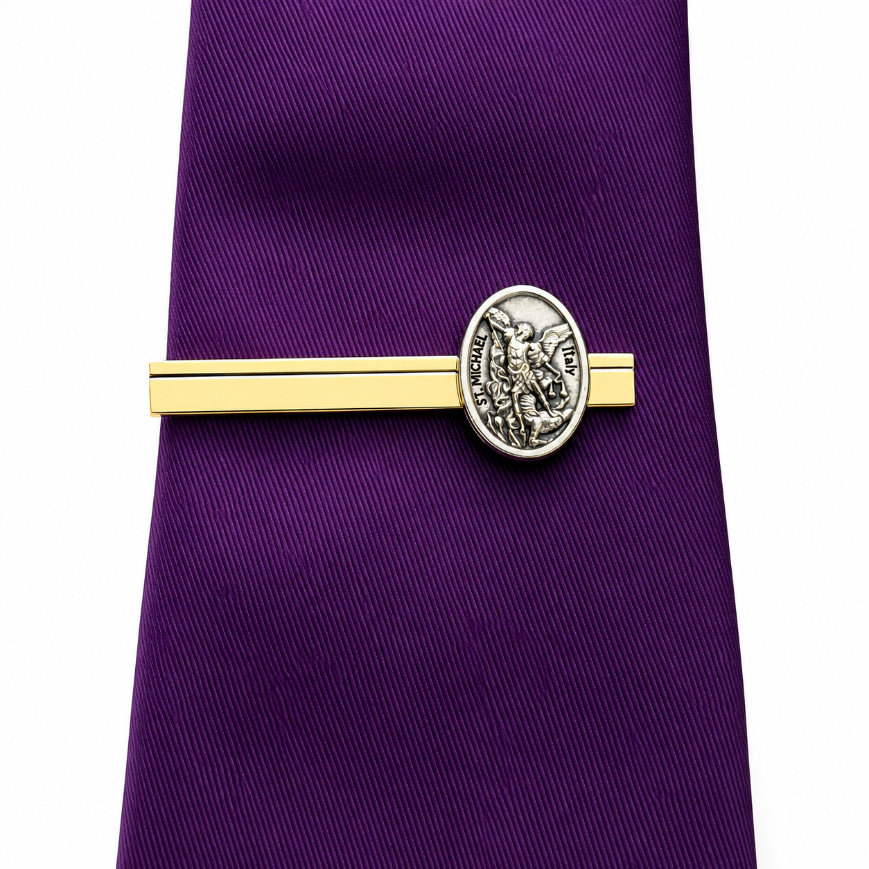 A purple necktie with a gold tie bar and a silver oval Saint Michael emblem, shown against a plain white background.