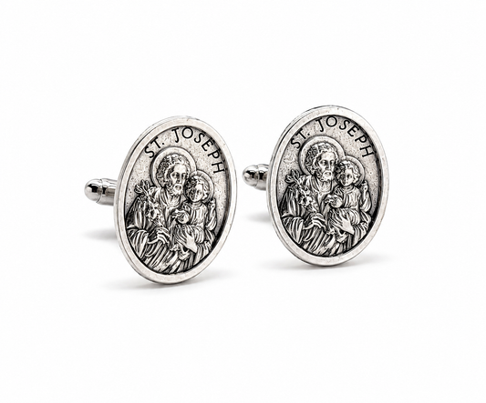 A pair of oval silver cufflinks featuring an embossed religious design of St. Joseph and child, with 'ST.