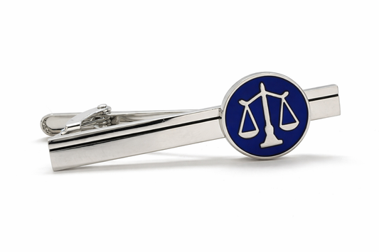 Silver tie clip with blue circular emblem featuring a scale design on a white background