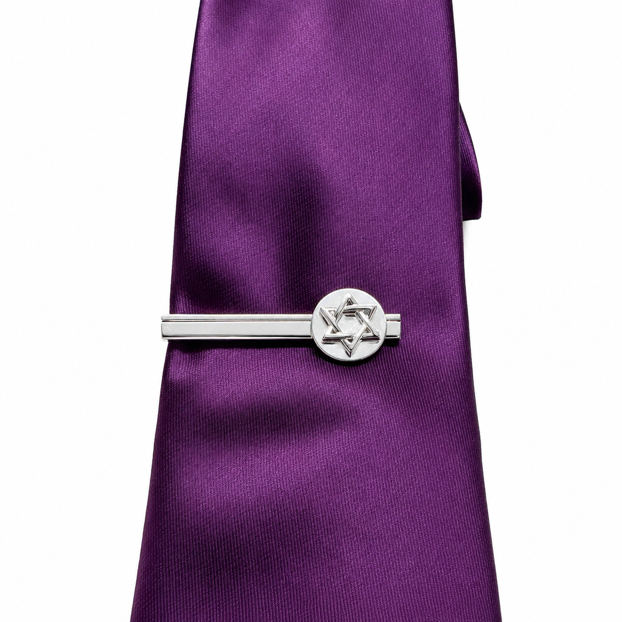 Silver tie clip with Star of David design on a purple tie against a white background