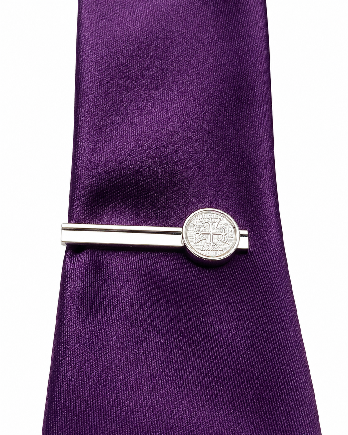 Silver tie clip on a purple tie against a white background