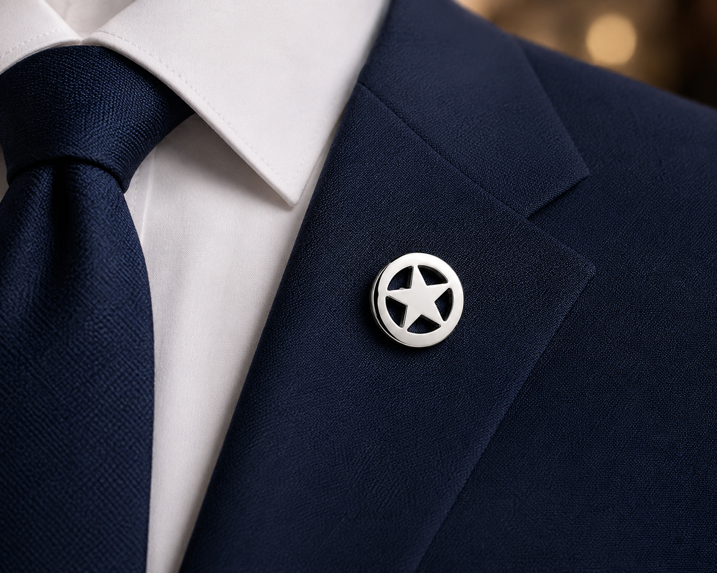 Navy suit jacket with a star lapel pin and navy tie on a blurred background