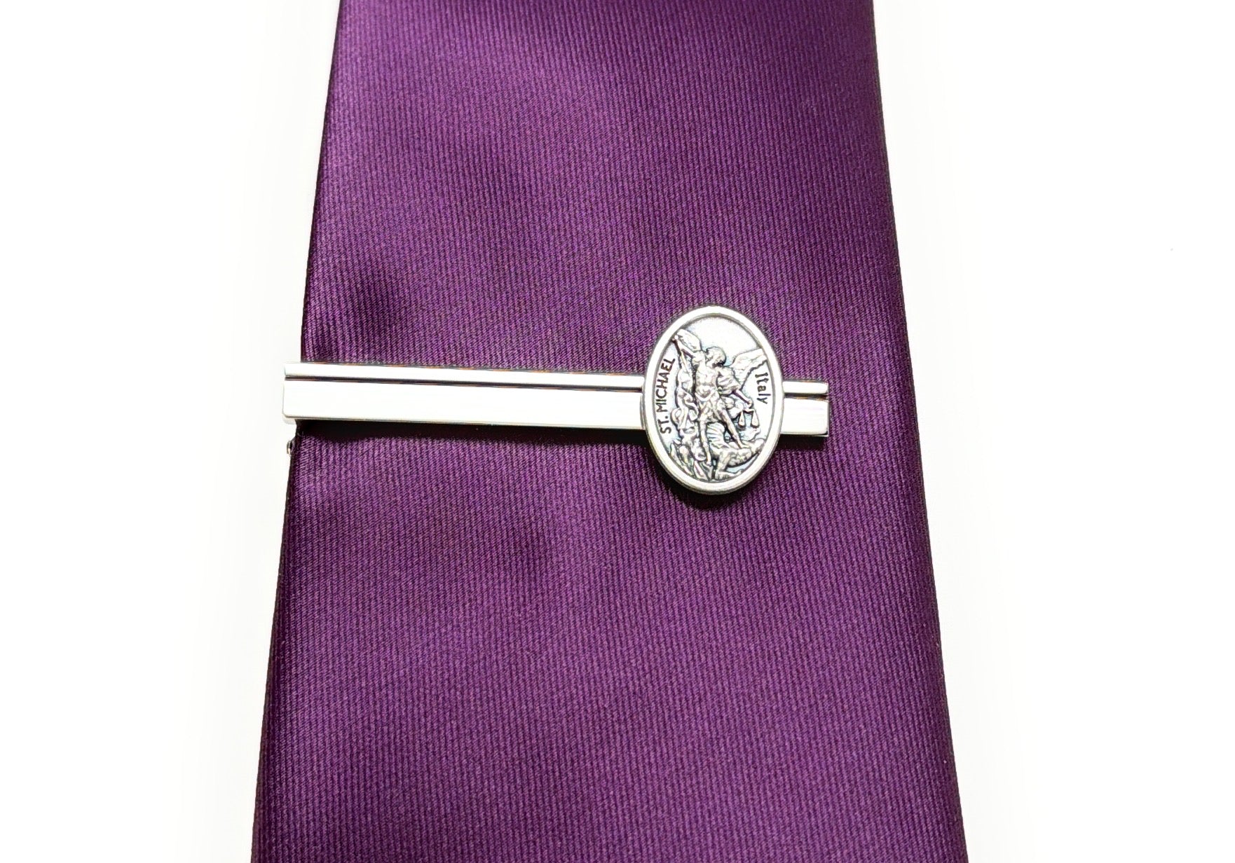 Silver tie clip on a purple tie against a white background