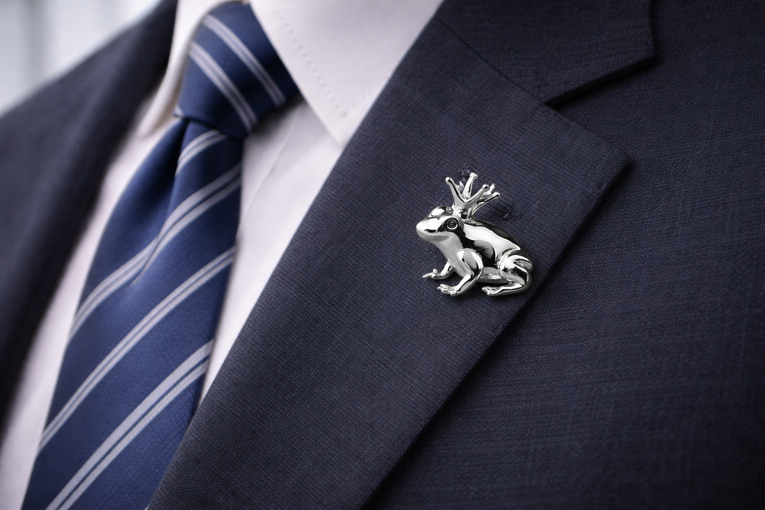 Silver frog lapel pin on a dark suit jacket with a striped tie.