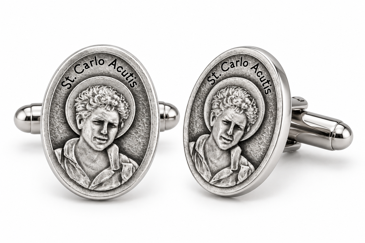 A pair of oval silver-toned cufflinks featuring a raised relief portrait of St. Carlo Acutis with the engraved text 'St.