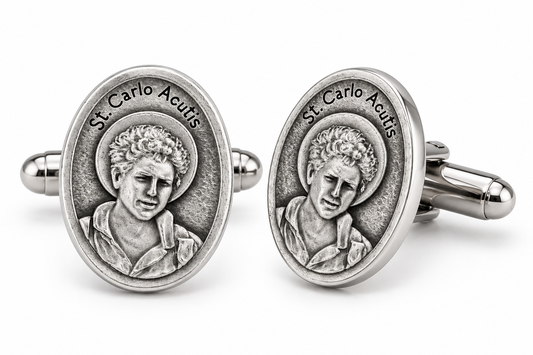 A pair of oval silver-toned cufflinks featuring a raised relief portrait of St. Carlo Acutis with the engraved text 'St.