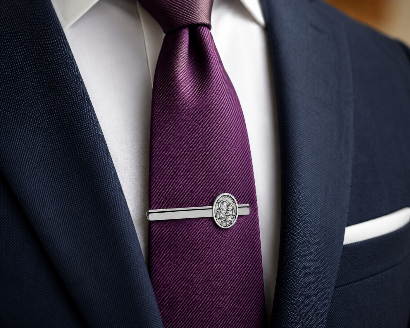 Navy suit with a purple tie and silver tie clip on a white shirt.