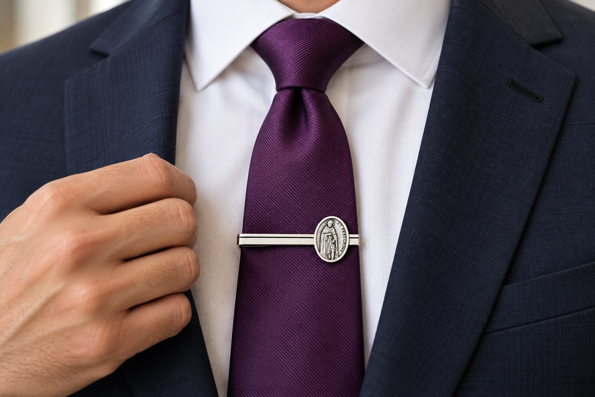 A close-up of a man wearing a dark navy suit jacket, white dress shirt, and a textured deep purple tie. He is adjusting the tie with one hand while wearing a silver-toned metal tie clip featuring an oval Saint Patrick design.