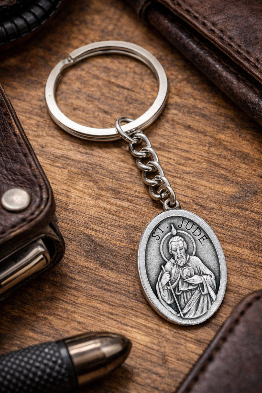 St Jude Catholic keychain with antique silver religious medal with religious pendant on a wooden surface