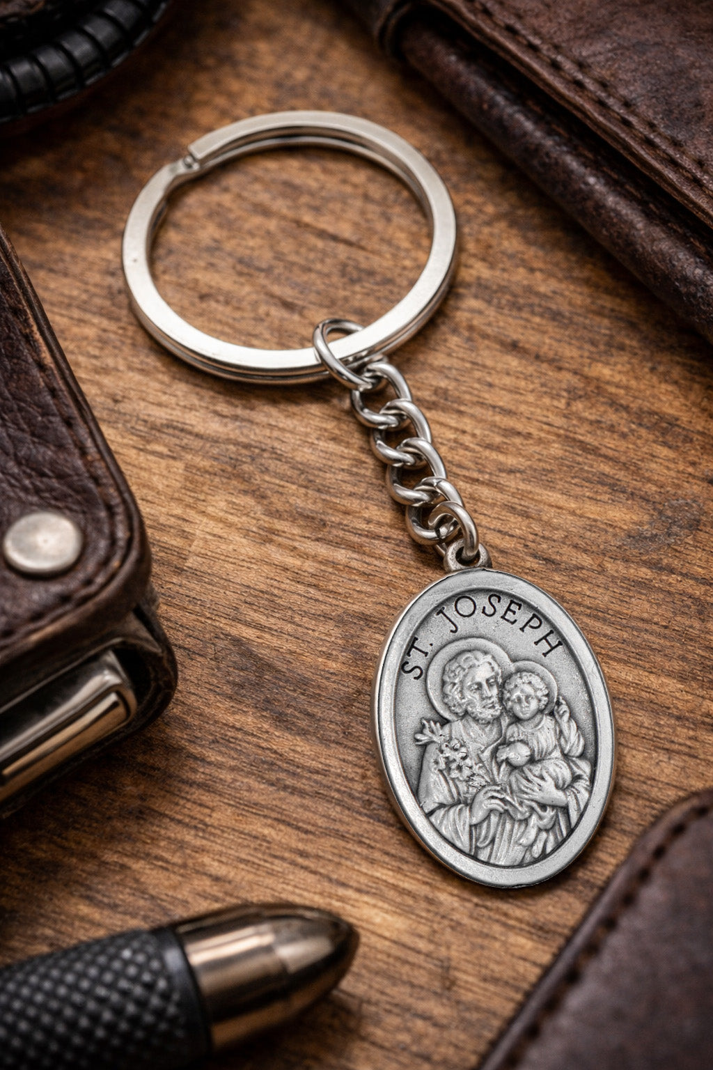 Silver keychain with St. Joseph pendant on a wooden surface