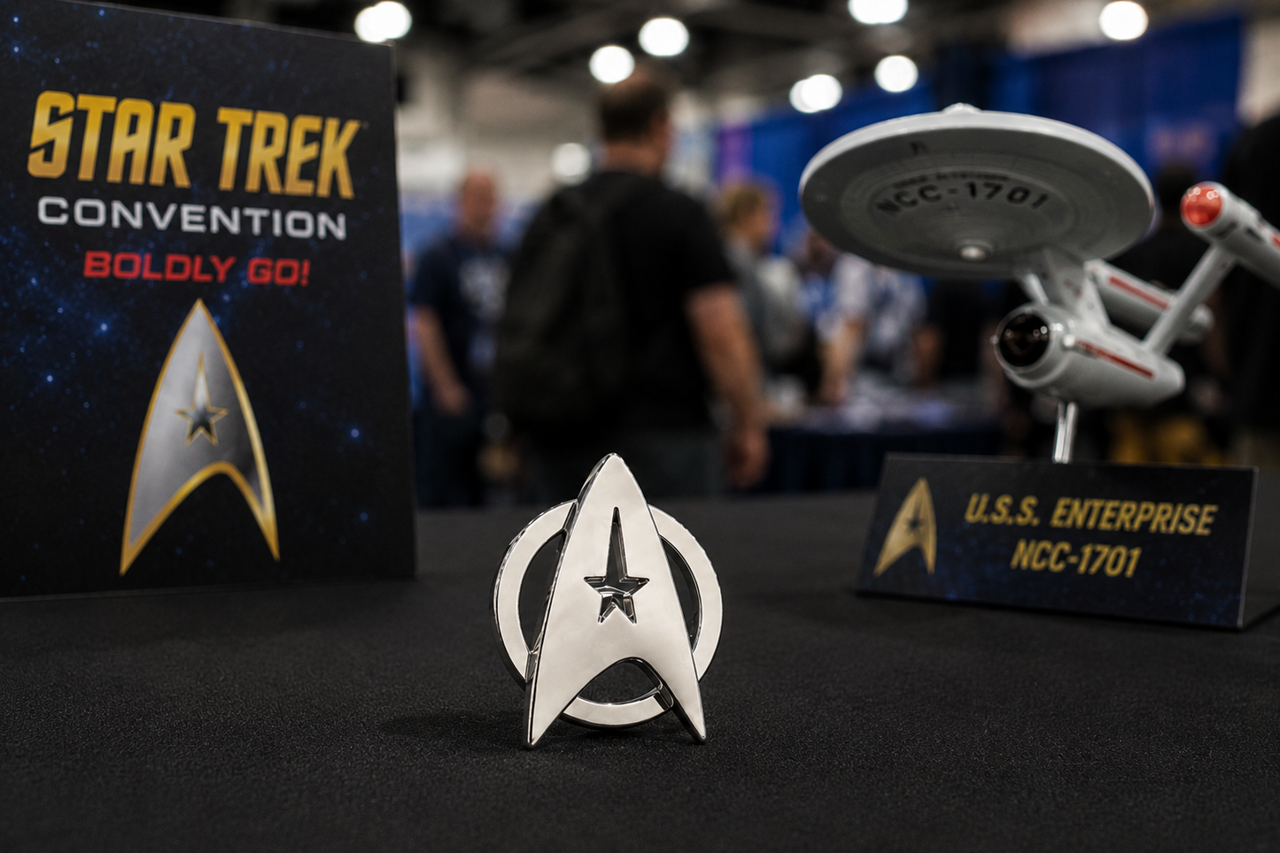 Star Trek convention badge and model ship with 'Star Trek Convention Boldly Go!' sign in the background.