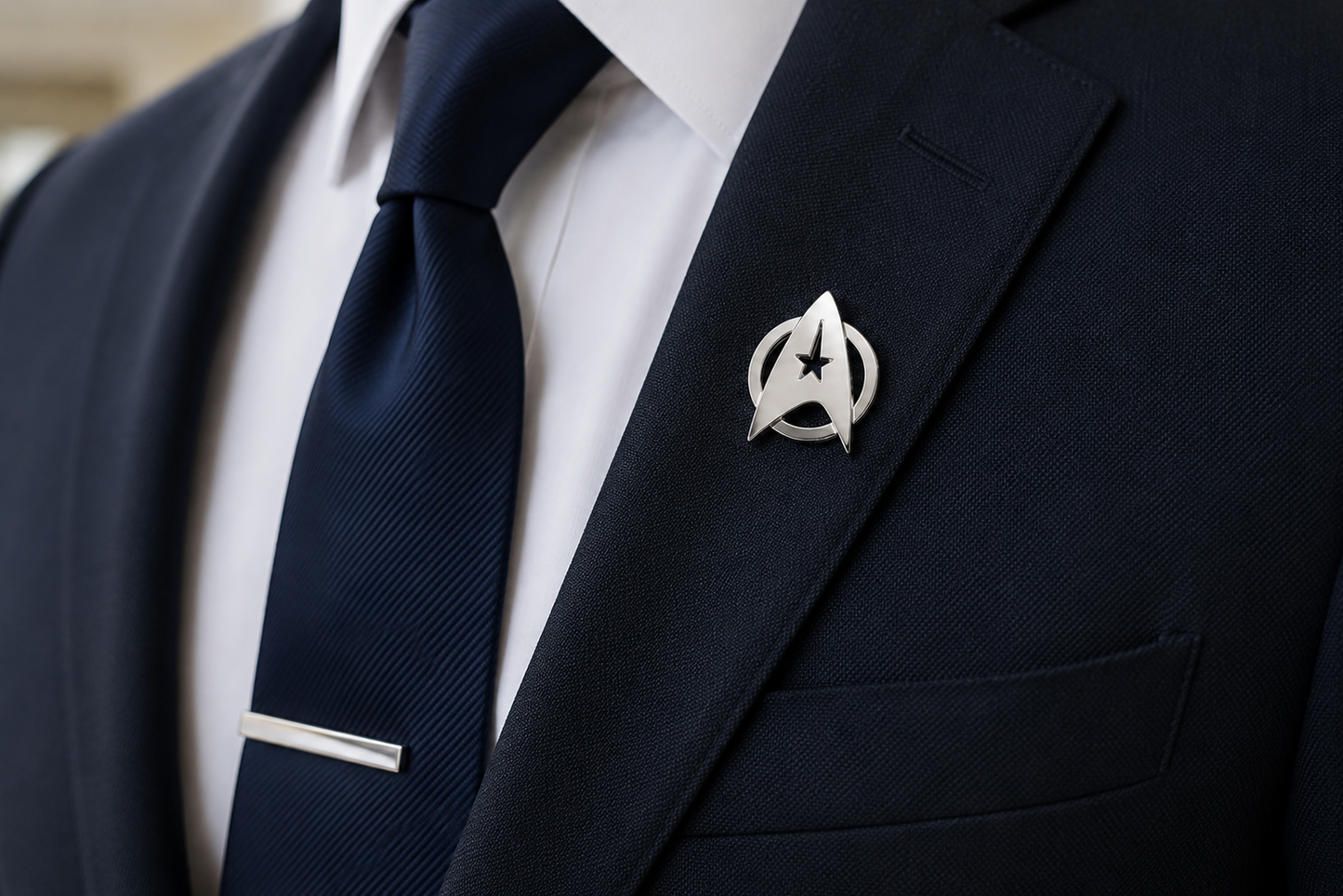 Navy suit with a white shirt, dark tie, and Star Trek logo lapel pin.