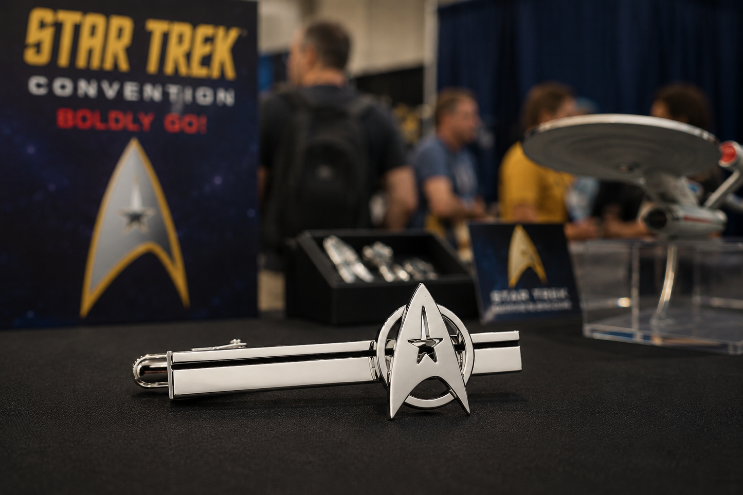 Star Trek-themed tie clip on display at a convention with 'Star Trek Convention' sign in the background.
