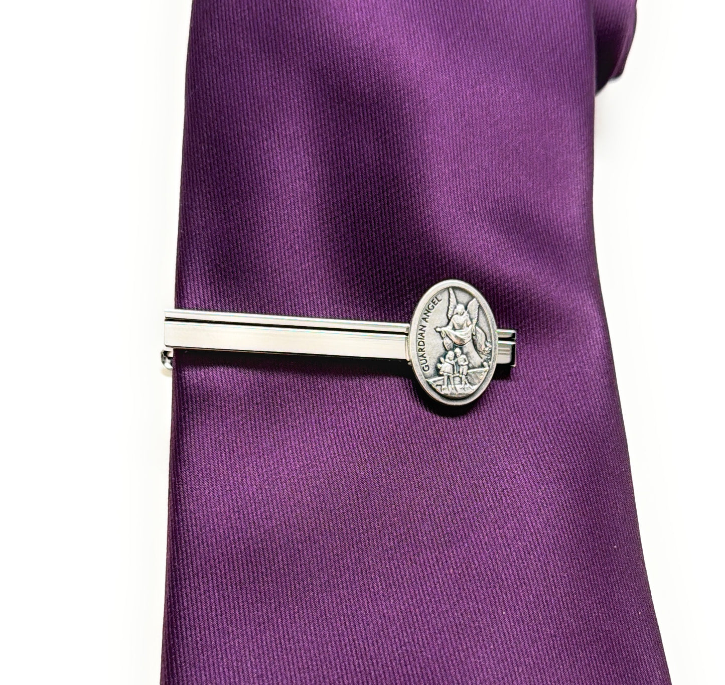 Silver tie clip on a purple tie against a white background