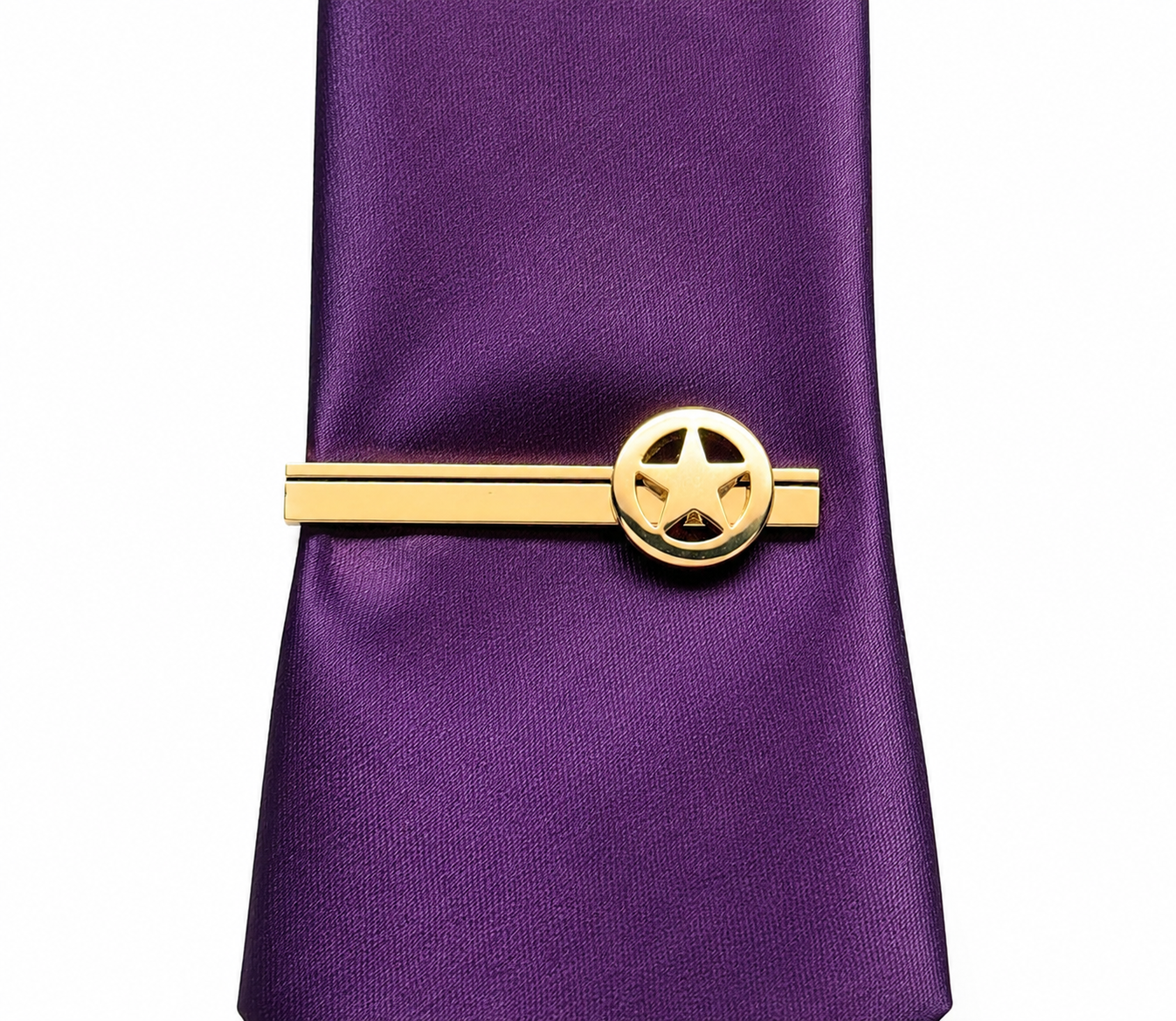 A purple necktie with a gold metal tie clip featuring a circular star emblem, shown against a plain white background.