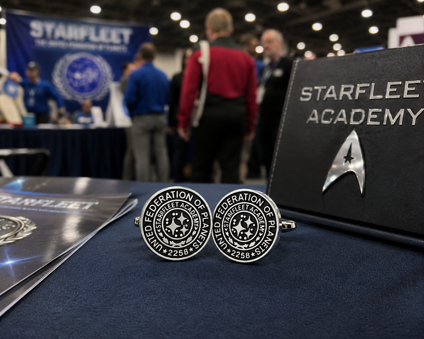 Star Trek-themed cufflinks with 'Starfleet Academy' book and promotional materials on a table.