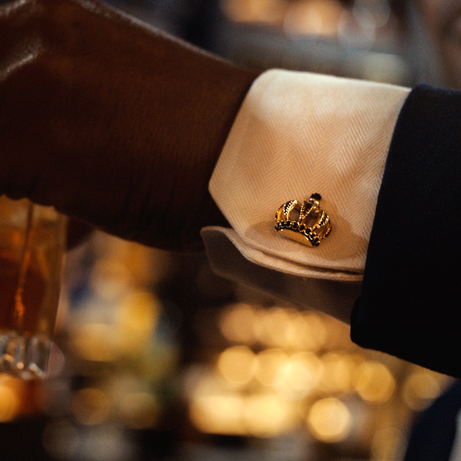 Close-up of a cufflink on a white shirt with a blurred bar background