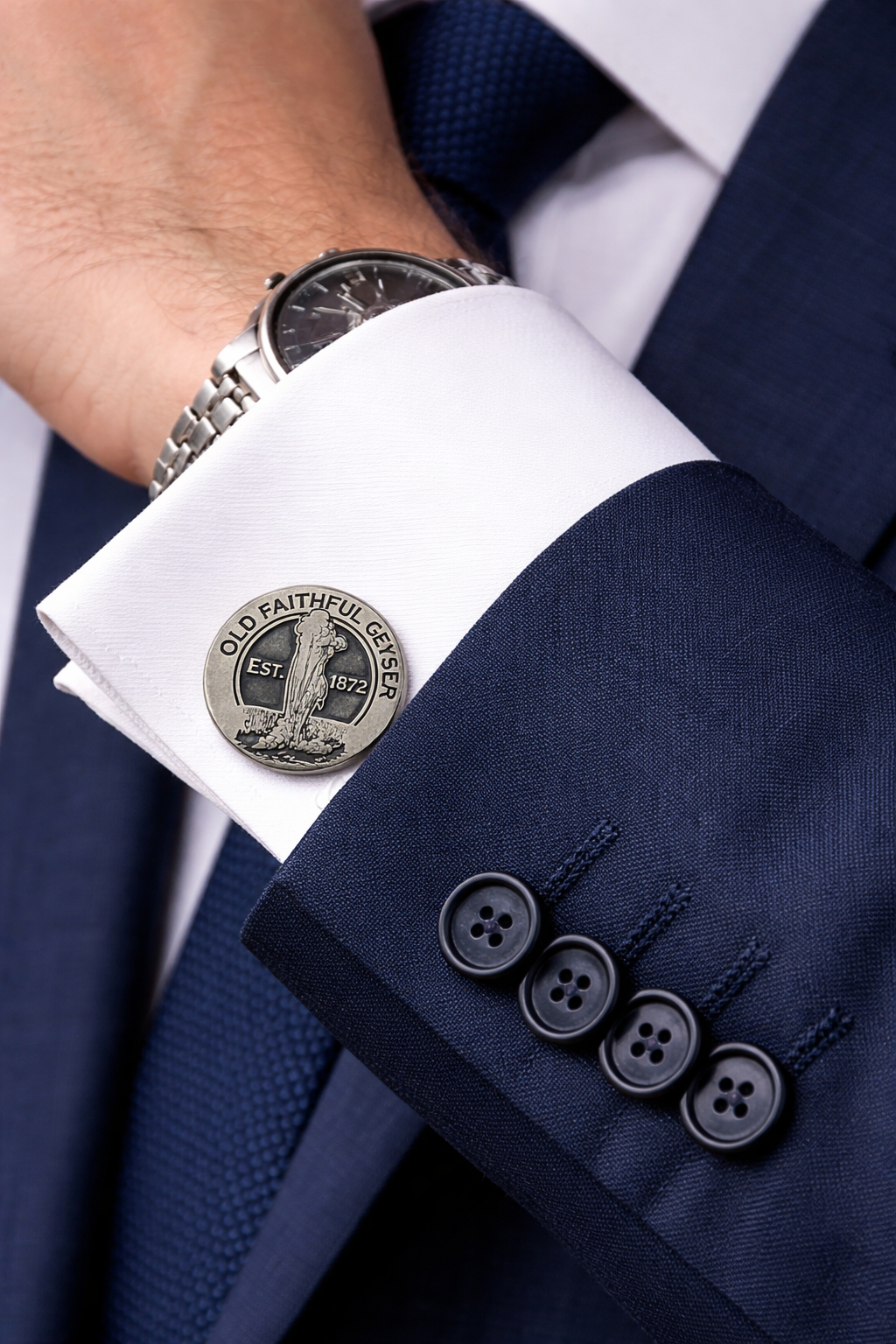 Close-up of a navy suit with cufflinks featuring a yellowstone old faithful geyser design.