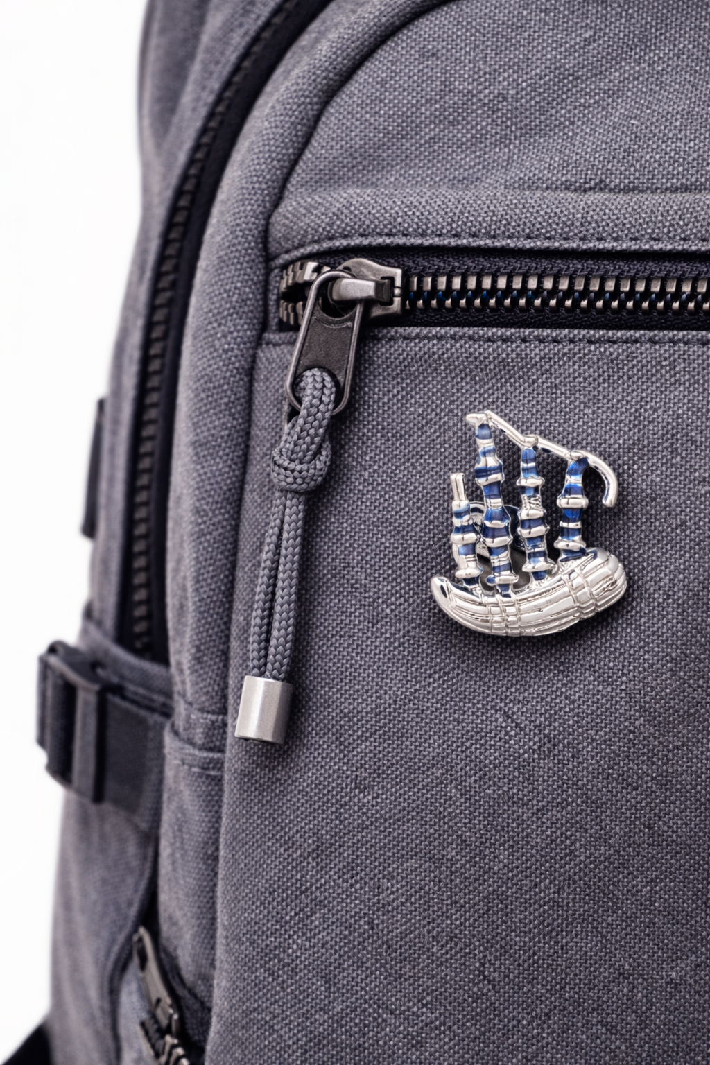 Gray backpack with a bagpipe Lapel Pin  emblem on a white background