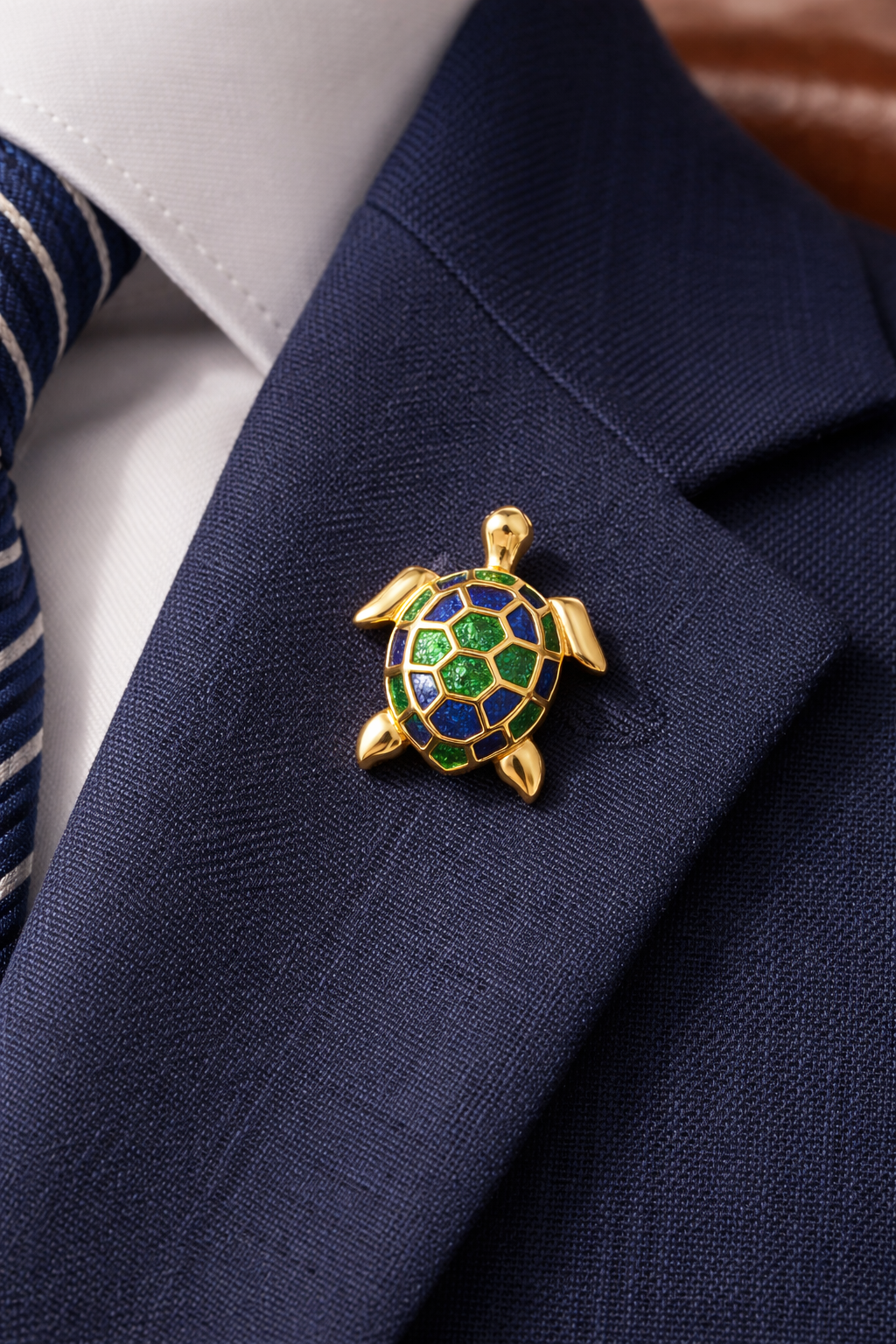 Close-up of the gold and green turtle enamel pin styled on the lapel of a dark navy blue suit jacket, demonstrating its size and how the jewel-toned colors pop against professional attire.