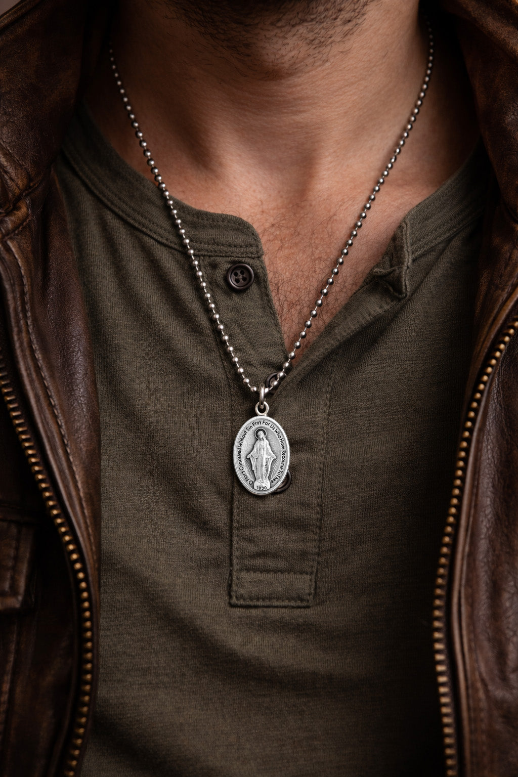 man wearing a green shirt and brown leather jacket with aMiraculous Medal Necklace featuring a pendant.