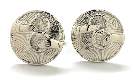 Pair of silver cufflinks with intricate design on a white background